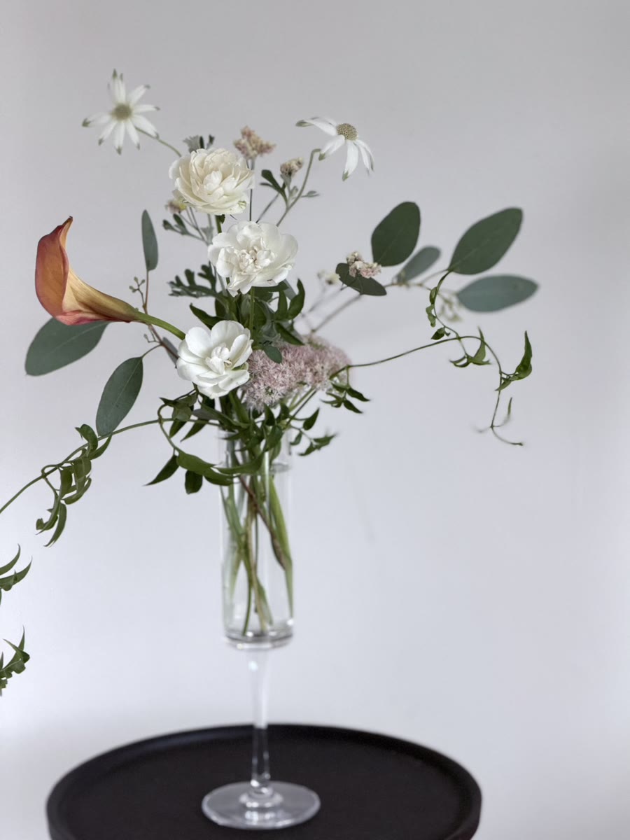 細長いグラス型の花瓶に生けられた、カラーと白い花・ユーカリのアレンジメント